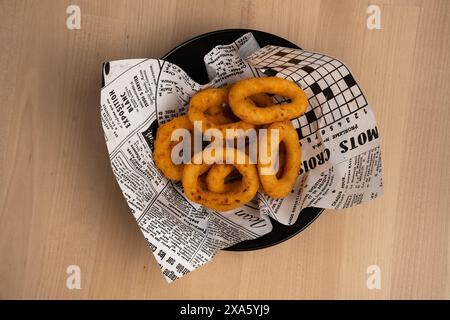 A small basket with onion rings on a wooden table Stock Photo