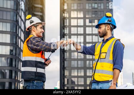 The construction workers shaking hands atop a building in Thailand, Bangkok Stock Photo