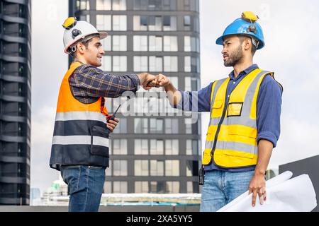 The construction workers shaking hands atop a building in Thailand, Bangkok Stock Photo