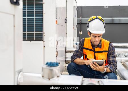 A construction worker in a hardhat using a digital tablet while sitting Stock Photo