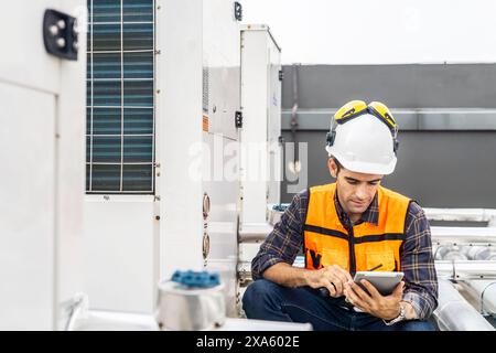 An engineer seated on the ground, browsing a tablet in Thailand, Bangkok Stock Photo