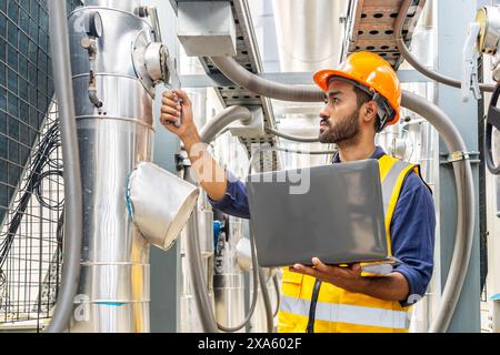 A man using a laptop in a manufacturing plant to work on a project in Thailand, Bangkok Stock Photo