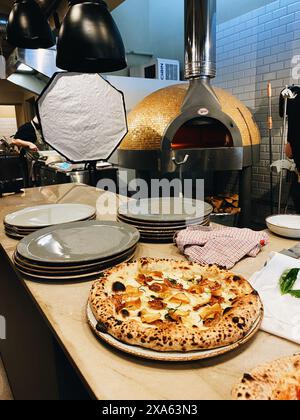 A kitchen interior with pizzas and plates on counters and multiple stoves Stock Photo