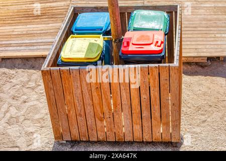 Colorful trash cans in wooden box.  Assorted bins on the street Stock Photo