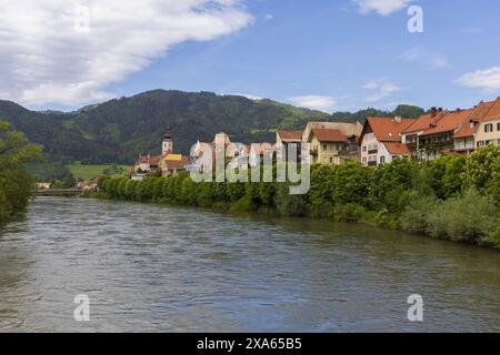 Panoramic photo across Mur river to medieval Austrian village across on summer sunny day, pastoral Alpine landscape Stock Photo