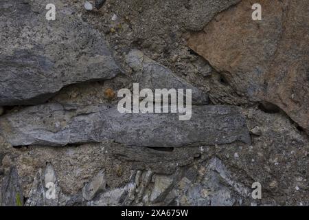 close-up photo of a textured dark gray stone wall surface in cracks and chips Stock Photo
