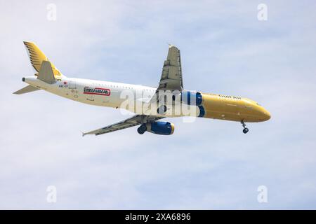 An airplane soaring through a clear blue sky with fluffy white clouds in Abu Dhabi, UAE Stock Photo