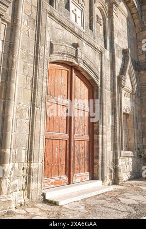 Old wooden door on a weathered stone Church of Timios Prodromos facade at Vouni village. Limassol District, Cyprus Stock Photo