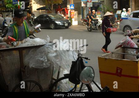 Refuse collector recycling cans and bottles from a bin on the streets of Hanoi, Vietnam. Stock Photo