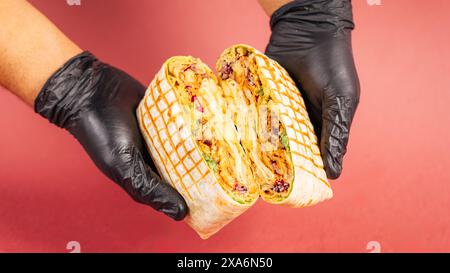 Black gloves holding up a traditional quesadilla with meat and tortilla Stock Photo