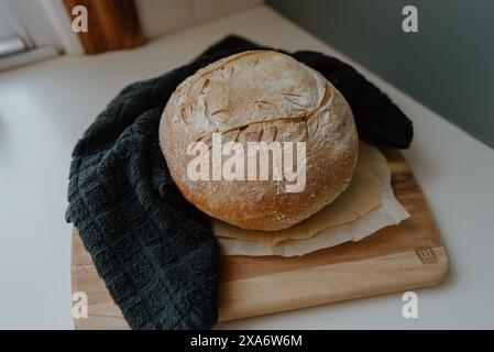 Loaf of bread on cutting board with towel Stock Photo
