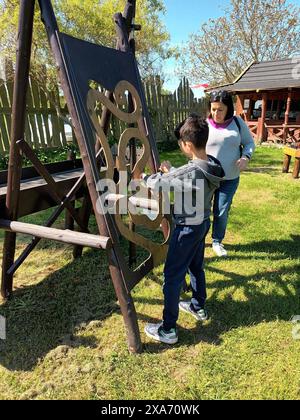 A boy playing with a large wooden object next to a woman Stock Photo