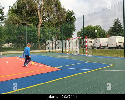 A shot of two children playing soccer on an outdoor court Stock Photo
