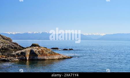 Looking over ocean to the distant mountains on the Olympic Peninsula, Washington, US. Stock Photo