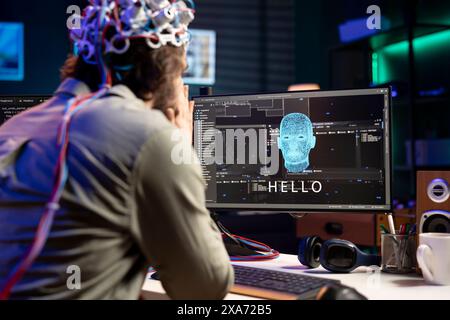 IT professional using EEG headset to communicate with artificial intelligence on computer in binary code. Software developer sending brainwave signals to AI entity on PC using high tech device Stock Photo