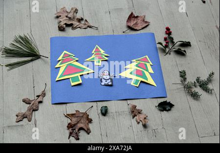 holiday themed arts and crafts for kids with colorful christmas trees and snowman (construction paper cut out with leaves) family activity for childre Stock Photo