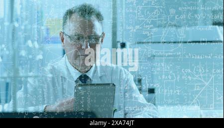 Image of mathematical and scientific formulas over male scientist using tablet Stock Photo
