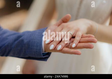 Two people, one in formal attire, holding hands affectionately Stock Photo