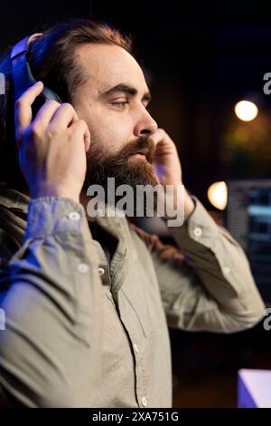 Computer engineer listening music while updating artificial intelligence neural networks, writing binary code script. IT professional enjoying music and upgrading high tech AI in home office Stock Photo