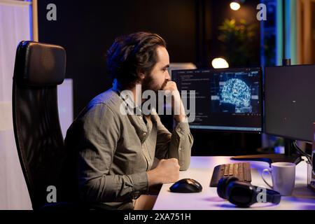 Programmer updating artificial intelligence deep learning algorithm, writing binary code scripts. IT specialist in apartment office uses programming to upgrade AI, waiting for software to load Stock Photo