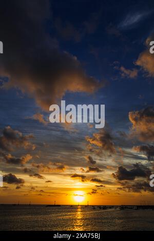 Sunset over peaceful ocean with cloudy sky Stock Photo