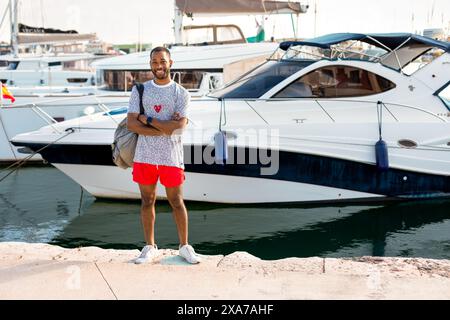 Man in red shorts posing by boats for photoshoot Stock Photo