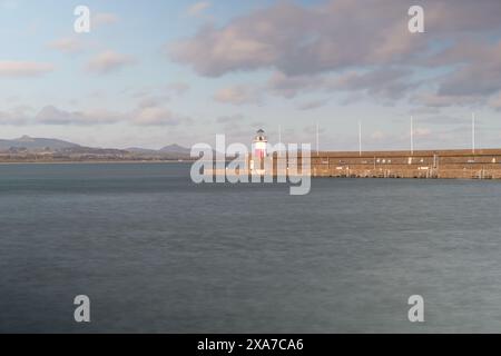 Lighthouse by the ocean under cloudy skies Stock Photo