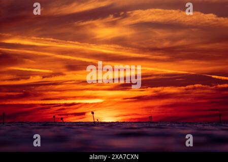 Vivid orange and yellow sunset over the ocean with cloudy skies Stock Photo