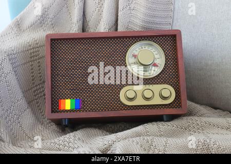 A vintage radio resting on white sofa in a living room with a rainbow flag logo on it Stock Photo