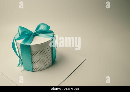 A square box with a turquoise bow atop white box Stock Photo