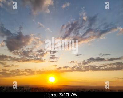 The sun sets behind the city, setting behind the horizon, picturesquely illuminating the various clouds with delicate colors Stock Photo