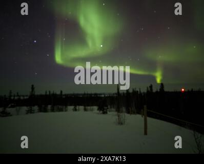 The vibrant northern lights illuminate the sky above a deserted road on a clear night Stock Photo