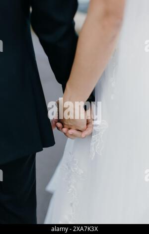 Two individuals hand in hand, gazing at the urban street ahead Stock Photo