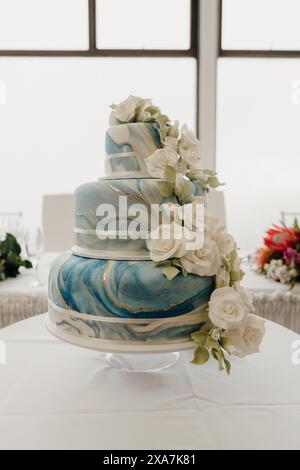 Large wedding cake decorated with white roses and blue frosting Stock Photo