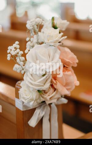 Floral arrangement adorns wooden church pew Stock Photo