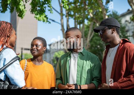 Happy African American friends classmates spending pleasant time together outdoors in sunny weather. Stock Photo