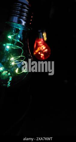 Glowing light bulb with colorful Christmas lights on dark background Stock Photo