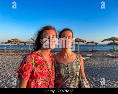 Two happy women on a beach by the ocean at sunset Stock Photo