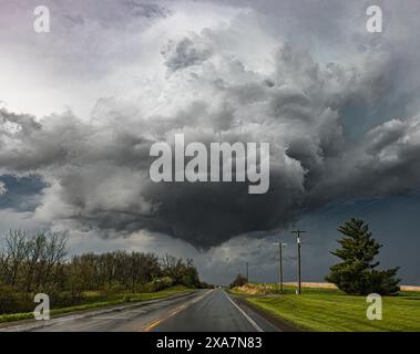 Dark clouds loom over a deserted road under a grey sky Stock Photo