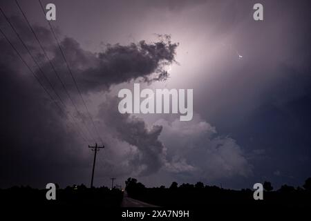 A car drives on a rural road at night during a lightning storm Stock Photo