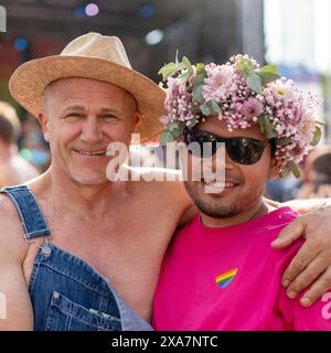 A beautiful gay couple smiling at camera with flowers in their hair Stock Photo