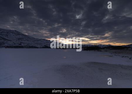 The Sun setting over snow-covered field Stock Photo