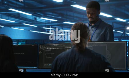 Supervisor in server hub workplace managing diverse team of developers looking for equipment software misconfigurations. Manager coordinating professionals mending data center bugs Stock Photo