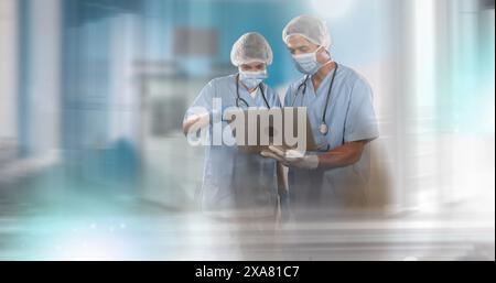 Image of male and female doctors wearing face masks using laptop Stock Photo