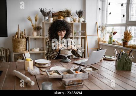 Female artist creating pottery in cozy studio with natural light Stock Photo