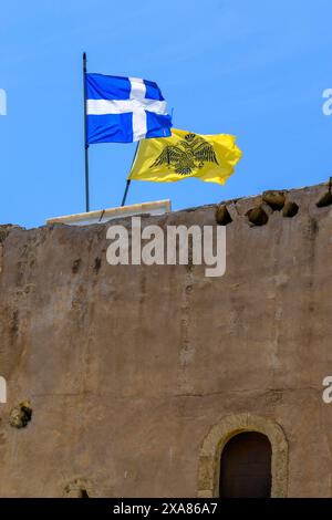 Top left flag of Greece behind it flag with symbol of Eastern Orthodox Greek Orthodox Church yellow background in black black imperial Byzantine Stock Photo