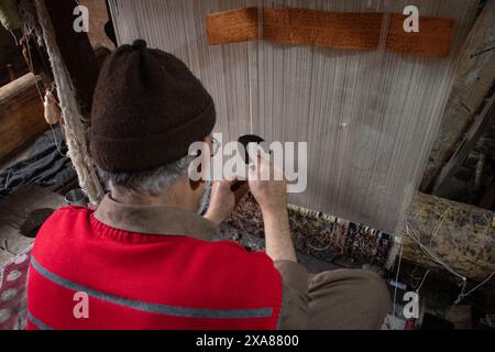 June 5, 2024, Srinagar, Jammu And Kashmir, India: A Kashmiri artisan weaves a traditional carpet at a factory in the old city of Srinagar. The history of Kashmiri carpets dates back to Hazrat Mir Syed Ali Hamdani, a Sufi mystic from Persia who introduced skilled artisans and carpet weaving to Kashmir via the Silk Route. The craft peaked during Zain-al-Abidin's reign, gaining global recognition. Traditionally, this art is passed down from father to son, preserving its intricate techniques and luxurious designs. (Credit Image: © Adil Abass/ZUMA Press Wire) EDITORIAL USAGE ONLY! Not for Commercia Stock Photo