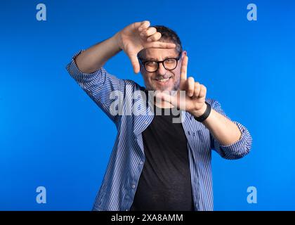 Adult man making a framing gesture with his hands - expressing creativity and positivity. Smile and gesture convey a sense of creative thinking, profe Stock Photo