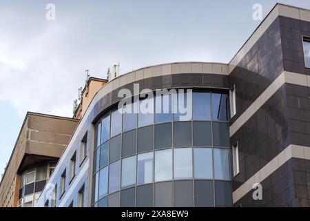 A modern curved building with many windows, against a cloudy urban sky. The tower block highlights innovative urban design, perfect for a city condomi Stock Photo