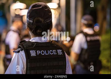 Hong Kong, China. 04th June, 2024. A female police officer watches as a man is detained and searched nearby in Victoria Park, Causeway Bay. Police were out in full force at the traditiional site of a memorial service for those who lost their lives during the Chinese government crackdown in Tiananmen Square on June 4, 1989. Police detained, searched, and removed several people who were attempting to commemorate the event. (Photo by Ben Marans/SOPA Images/Sipa USA) Credit: Sipa USA/Alamy Live News Stock Photo